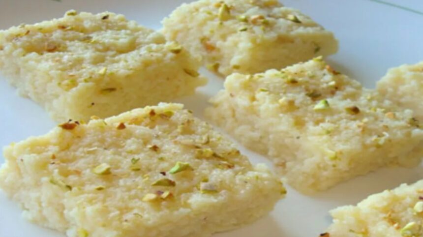 Homemade Kalakand garnished with chopped pistachios and almonds on a serving plate.